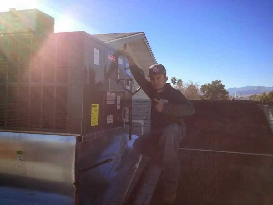 HVAC technician performing Air Duct Cleaning on a rooftop unit in Bluffdale